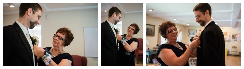 A groom has his boutonniere pinned on by his mother.